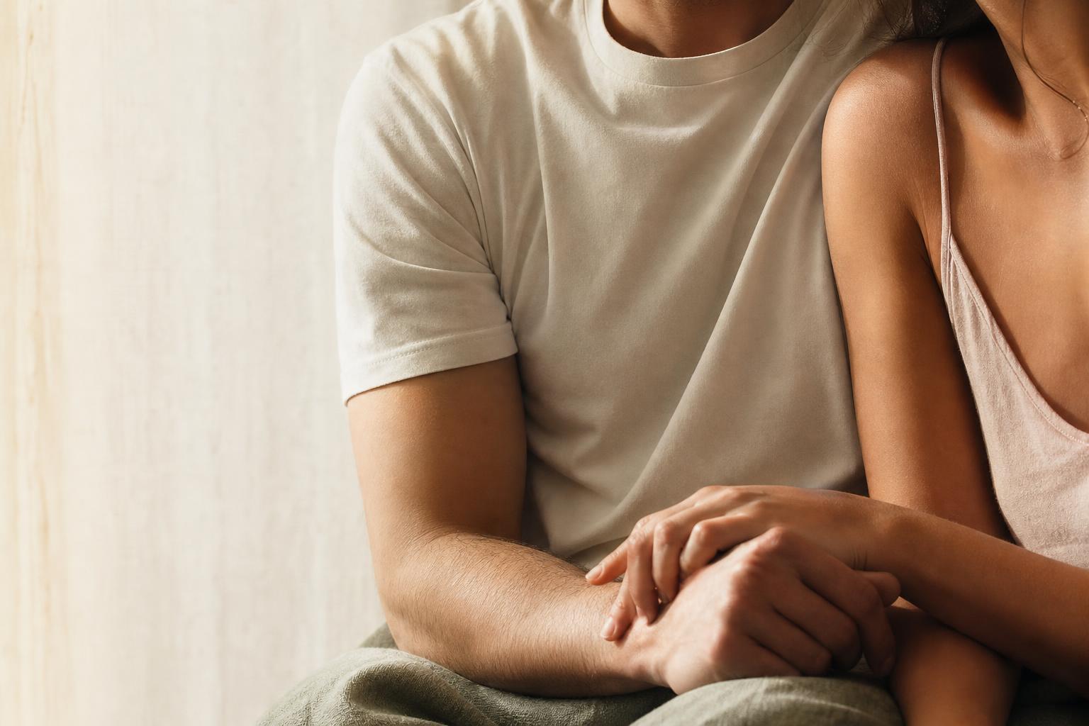 A couple in a quiet, intimate moment — hands gently resting together